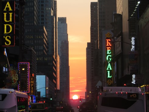 The setting sun aligns with the Manhattan skyscrapers